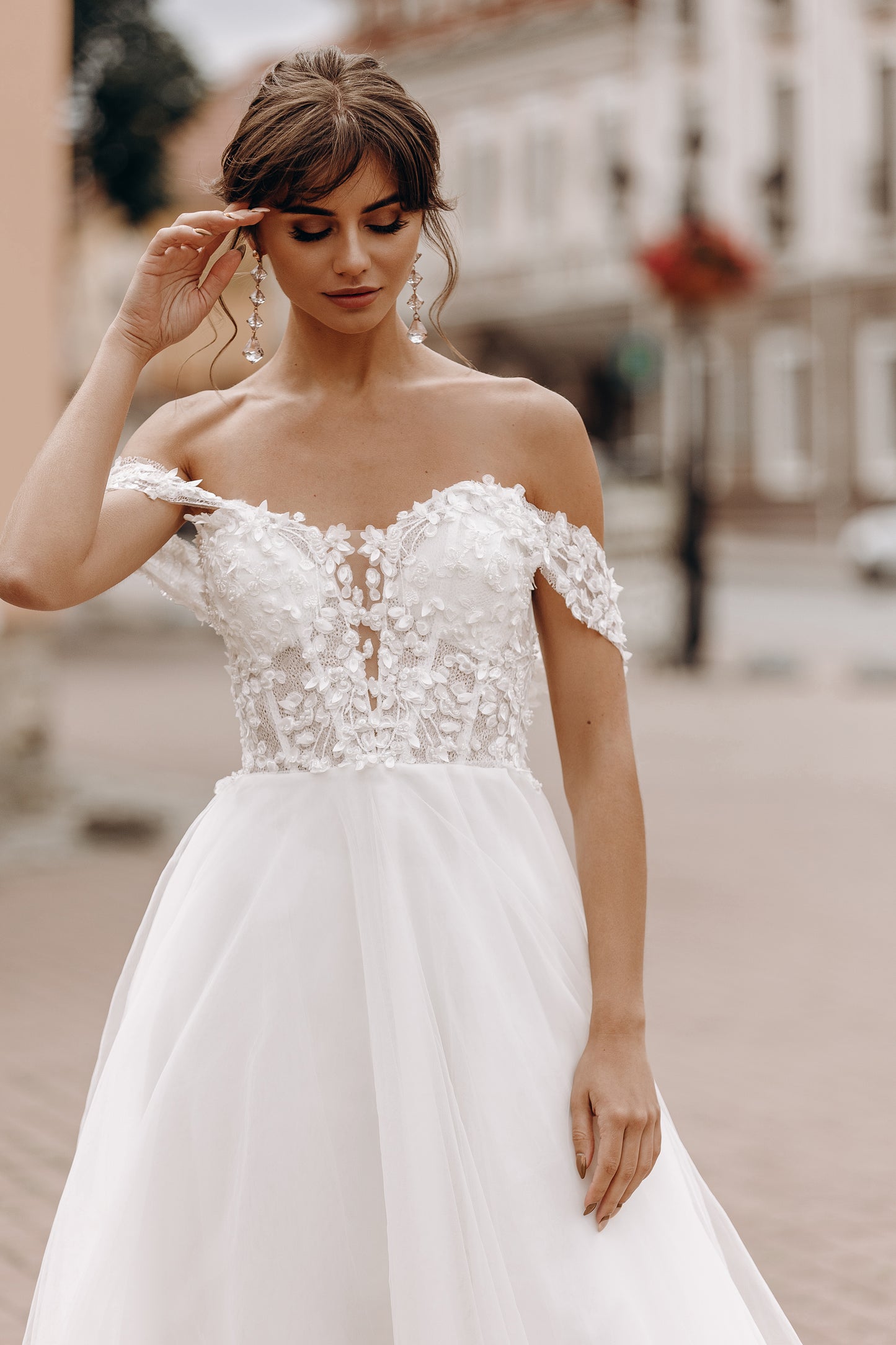 Bride holding train of soft tulle skirt with romantic floral lace accents