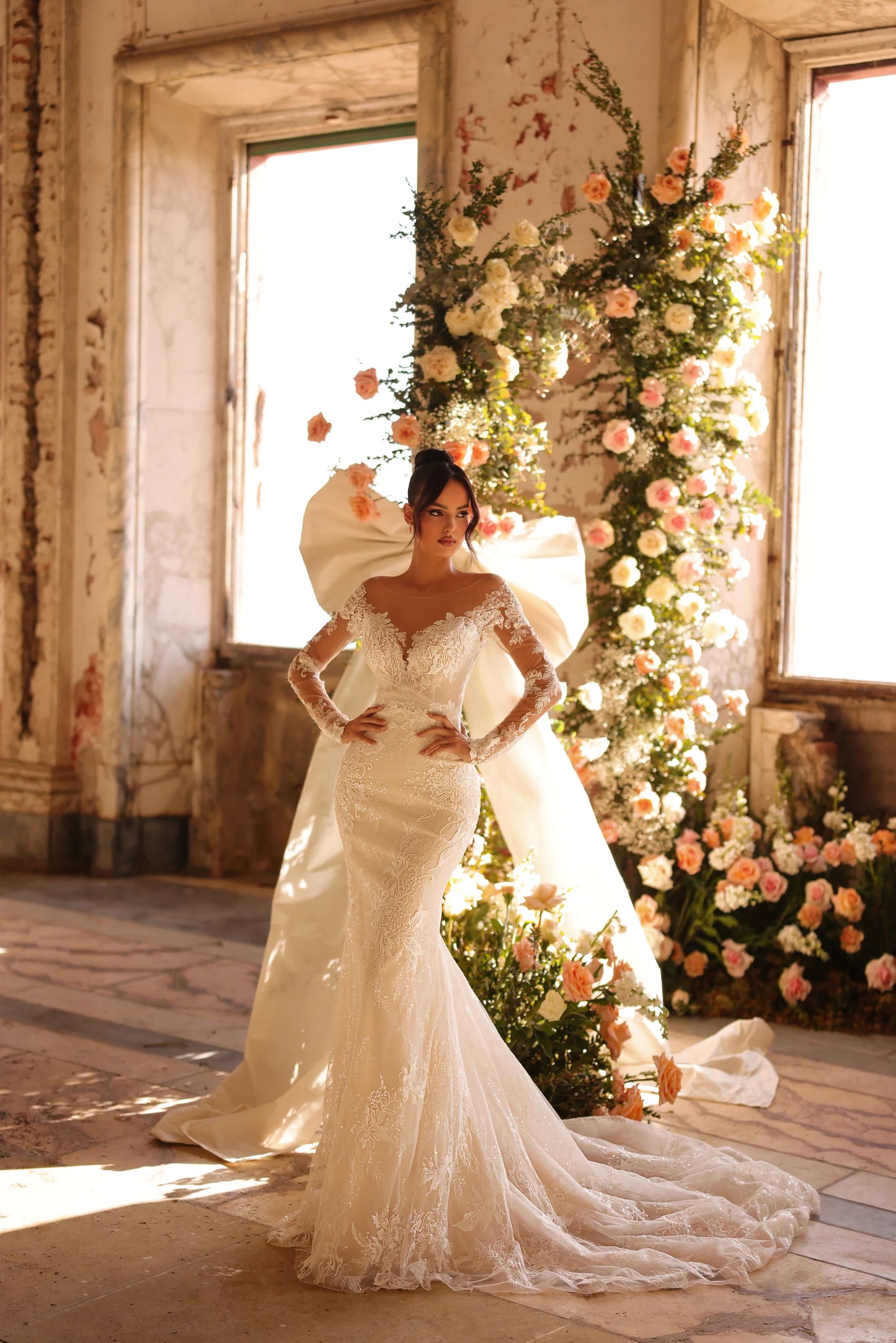 Bride in fitted lace gown with sheer long sleeves and soft train