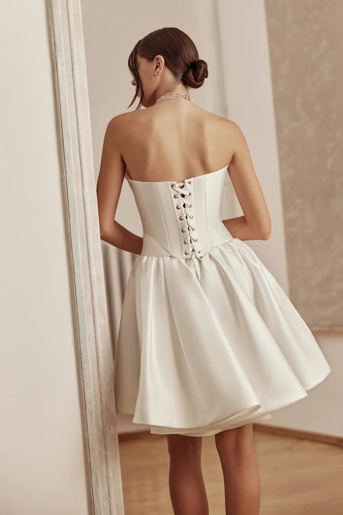 Close-up side profile of bride in a satin tea-length wedding dress with fitted bodice and soft pleats.