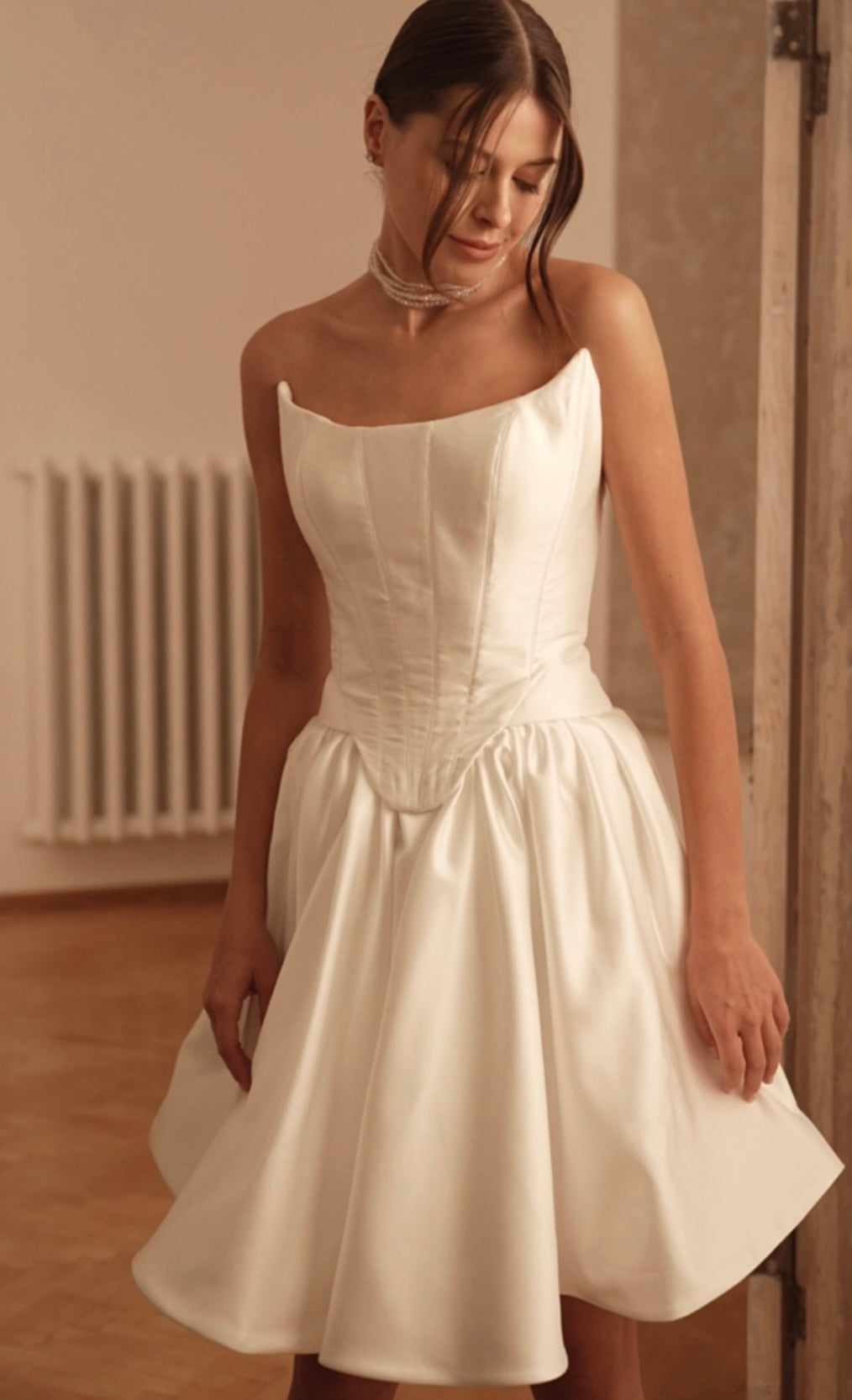 Bride gently twirling in tea-length wedding dress with square neckline, creating a playful, elegant look.