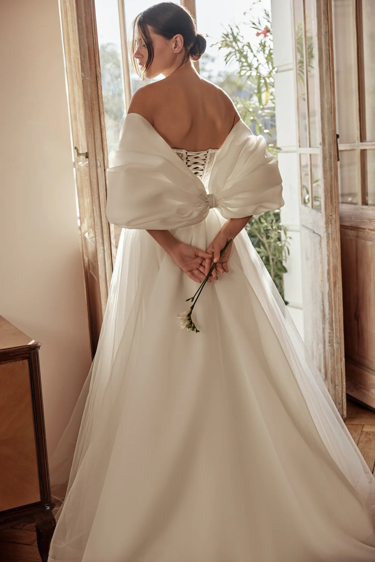 Back view of the bride showcasing the voluminous tulle skirt and delicate off-shoulder sleeves