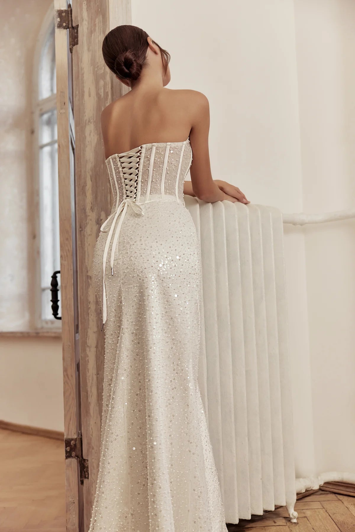 Back view of the ivory sheath gown featuring a flowing cape and fitted silhouette