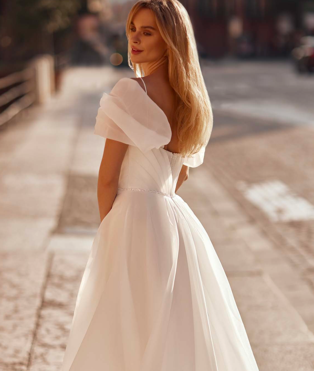 Flowing wedding gown with delicate shimmer, statement sleeves, and a romantic train