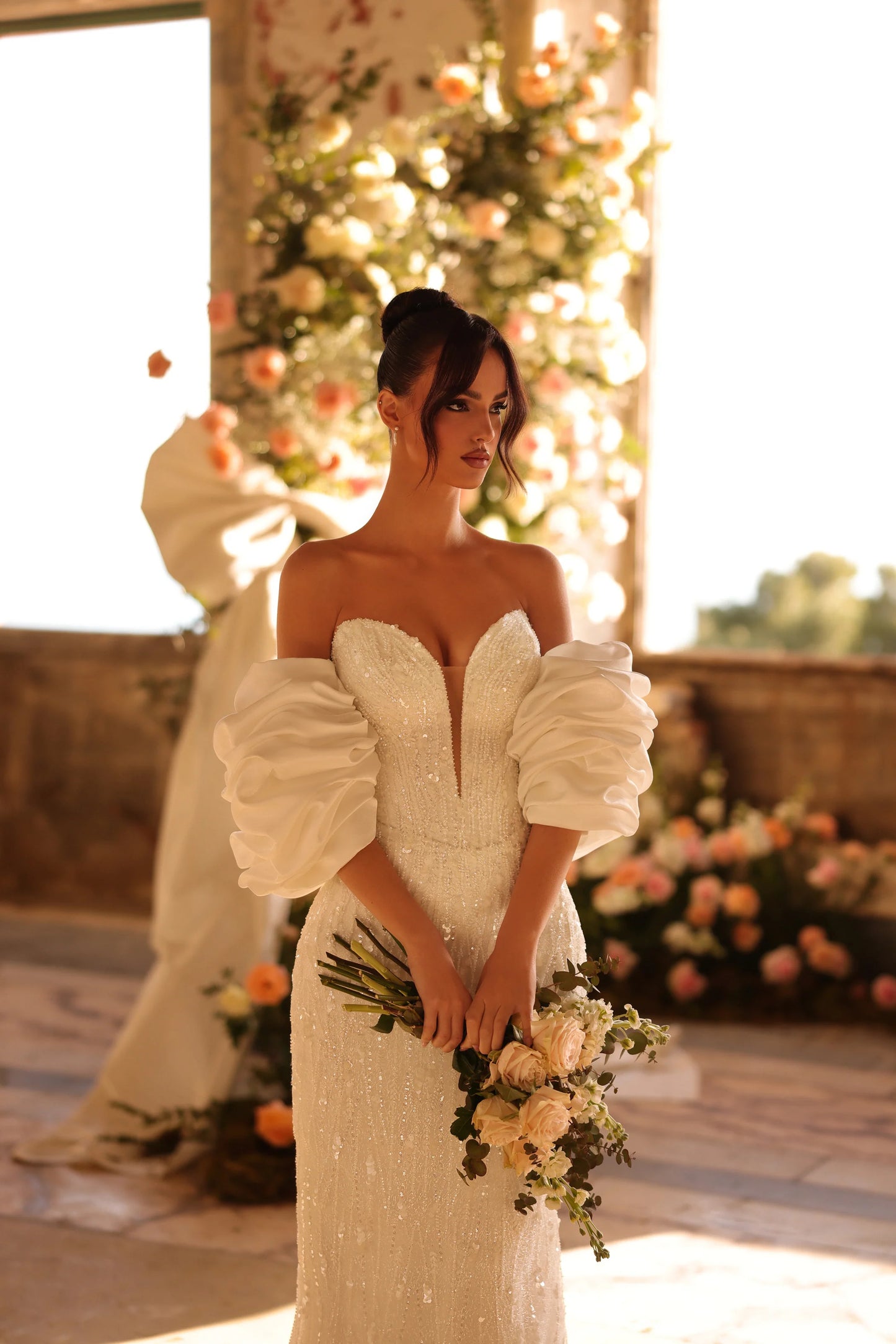 Bride in fitted wedding dress with dramatic puff sleeves and bouquet