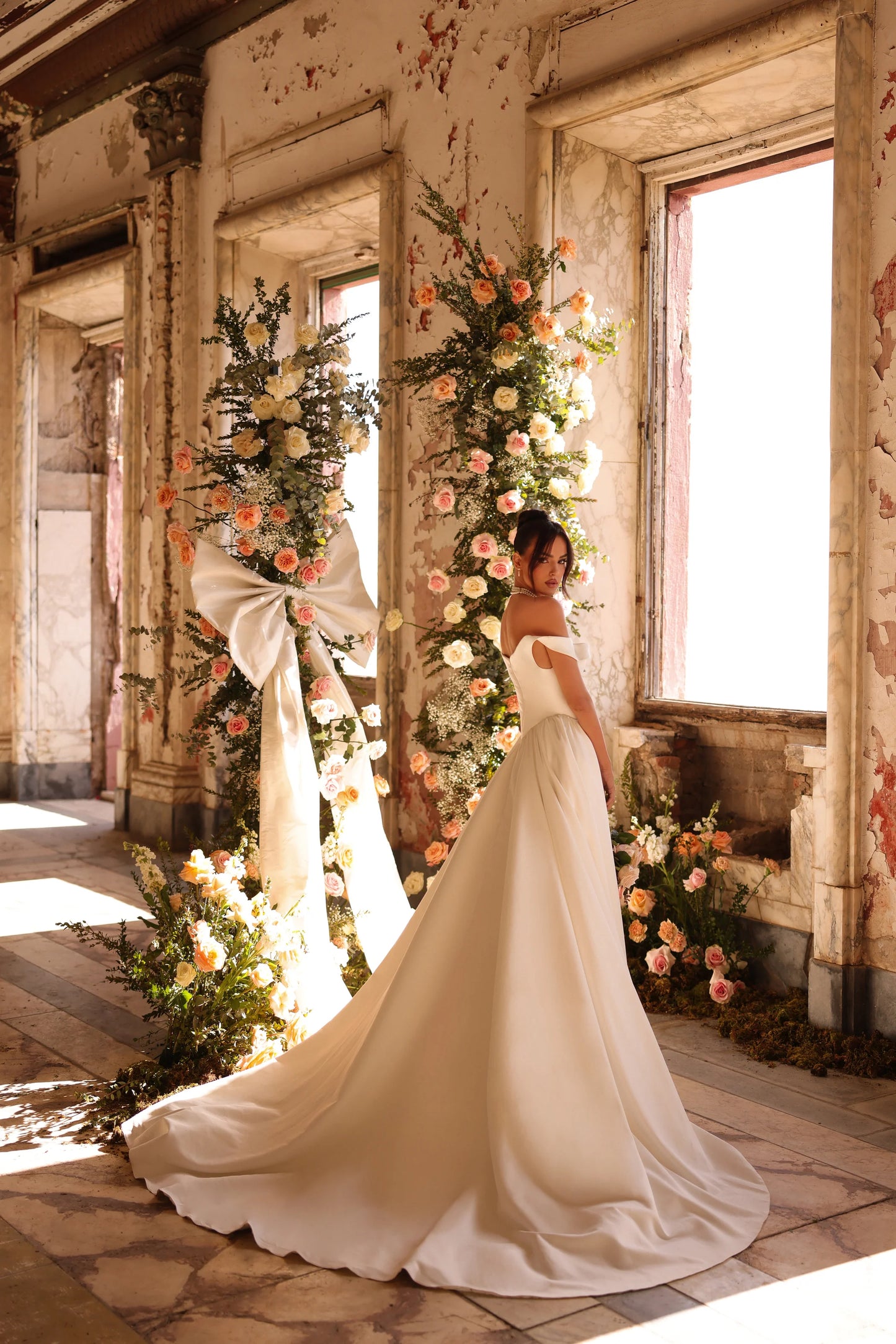 Back of bridal gown with flowing train and romantic indoor setting