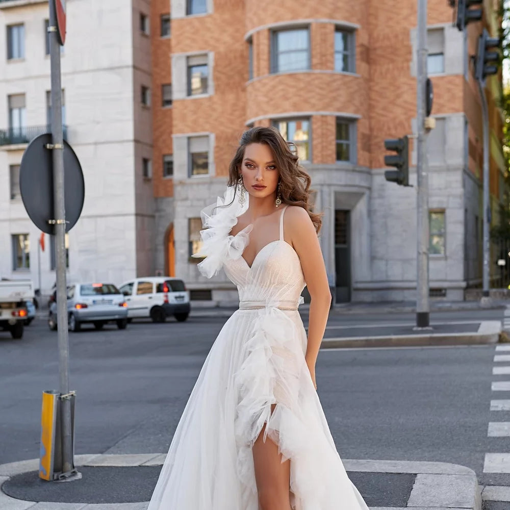 Close-up of a bride wearing an elegant wedding dress with a ruffled shoulder detail and flowing tulle skirt.