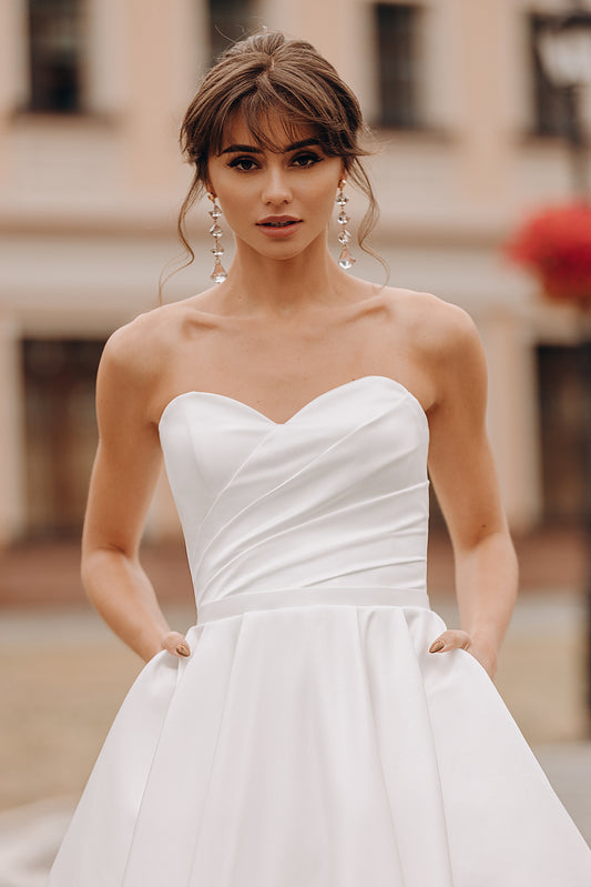 Bride in strapless sweetheart wedding gown with full A-line skirt, outdoors