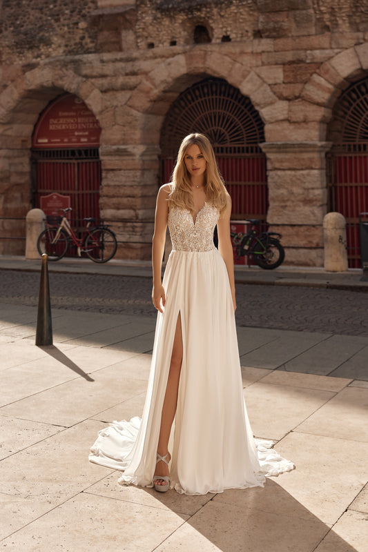 Woman in a white dress standing on a stone pavement with a stone building in the background