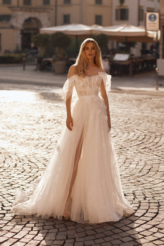 Woman in a white wedding dress standing on a cobblestone street.