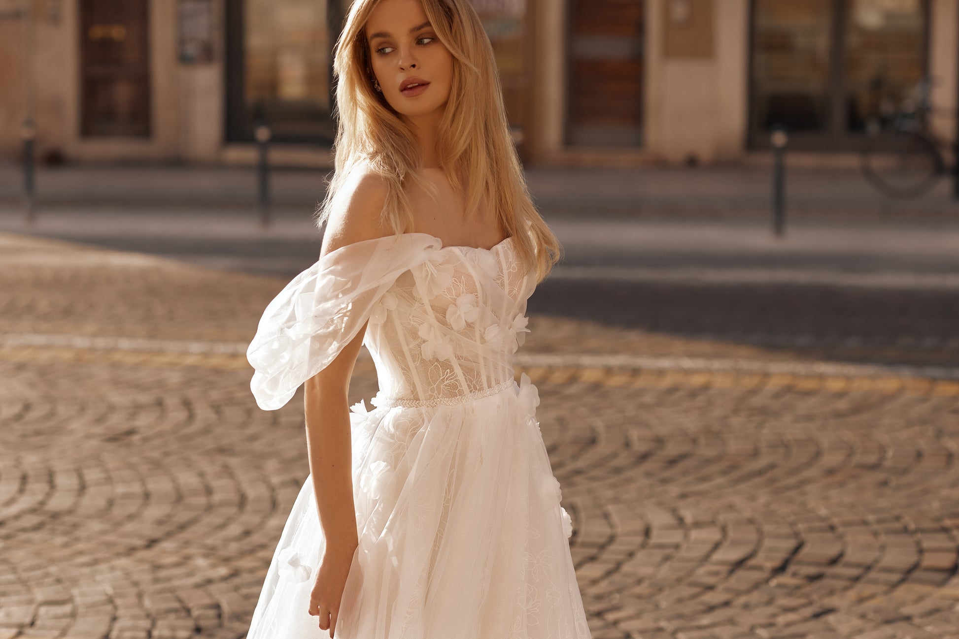 Woman in a white dress standing on a cobblestone street