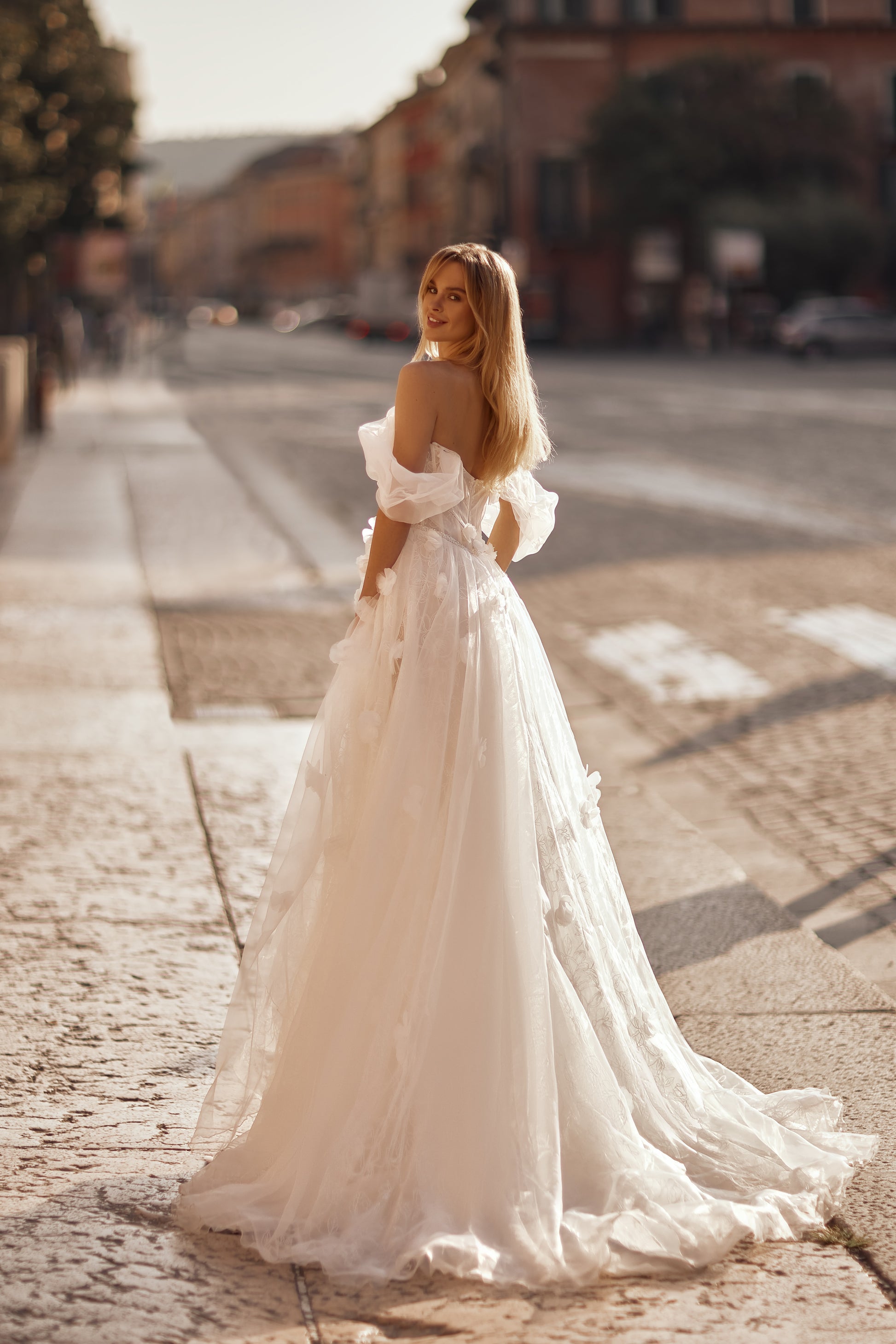 Wedding dress with layered tulle skirt, floral embellishments, and a slim belt