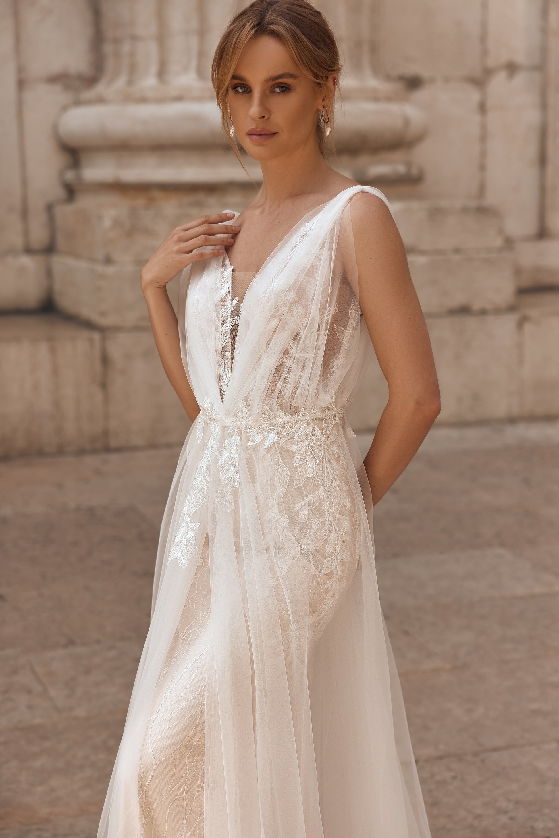 Woman wearing a white lace dress standing in front of classical architecture.