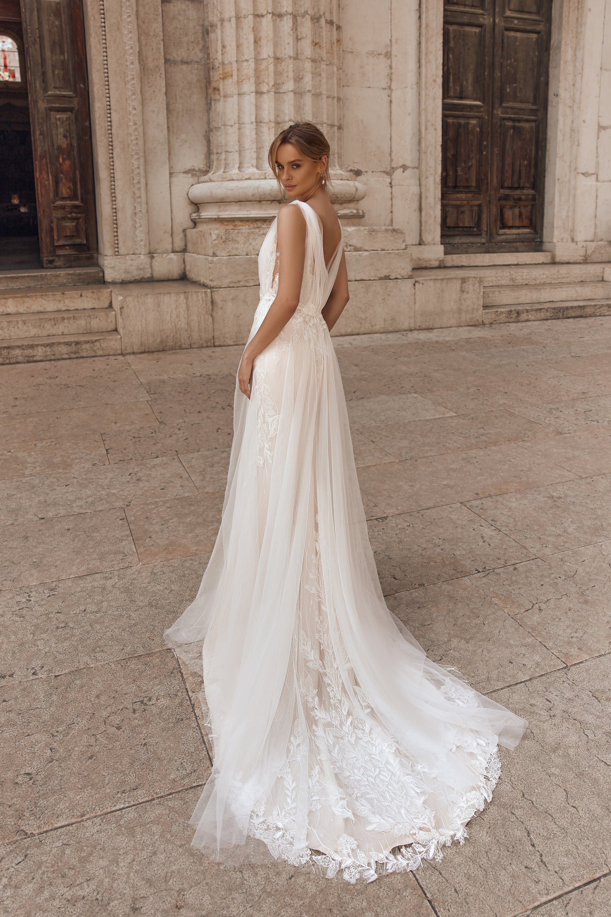 Bride in a romantic wedding dress featuring a flowing cape and floral accents