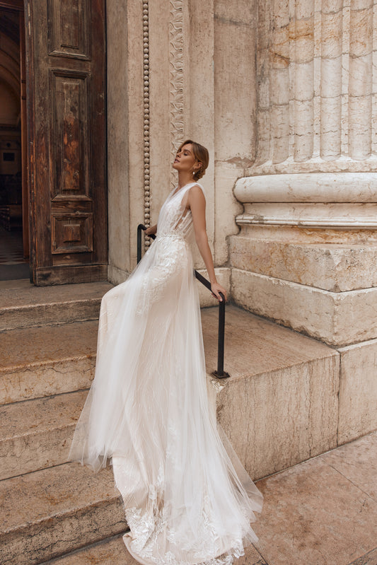 Bride wearing an ivory tulle wedding dress with floral details and a long train