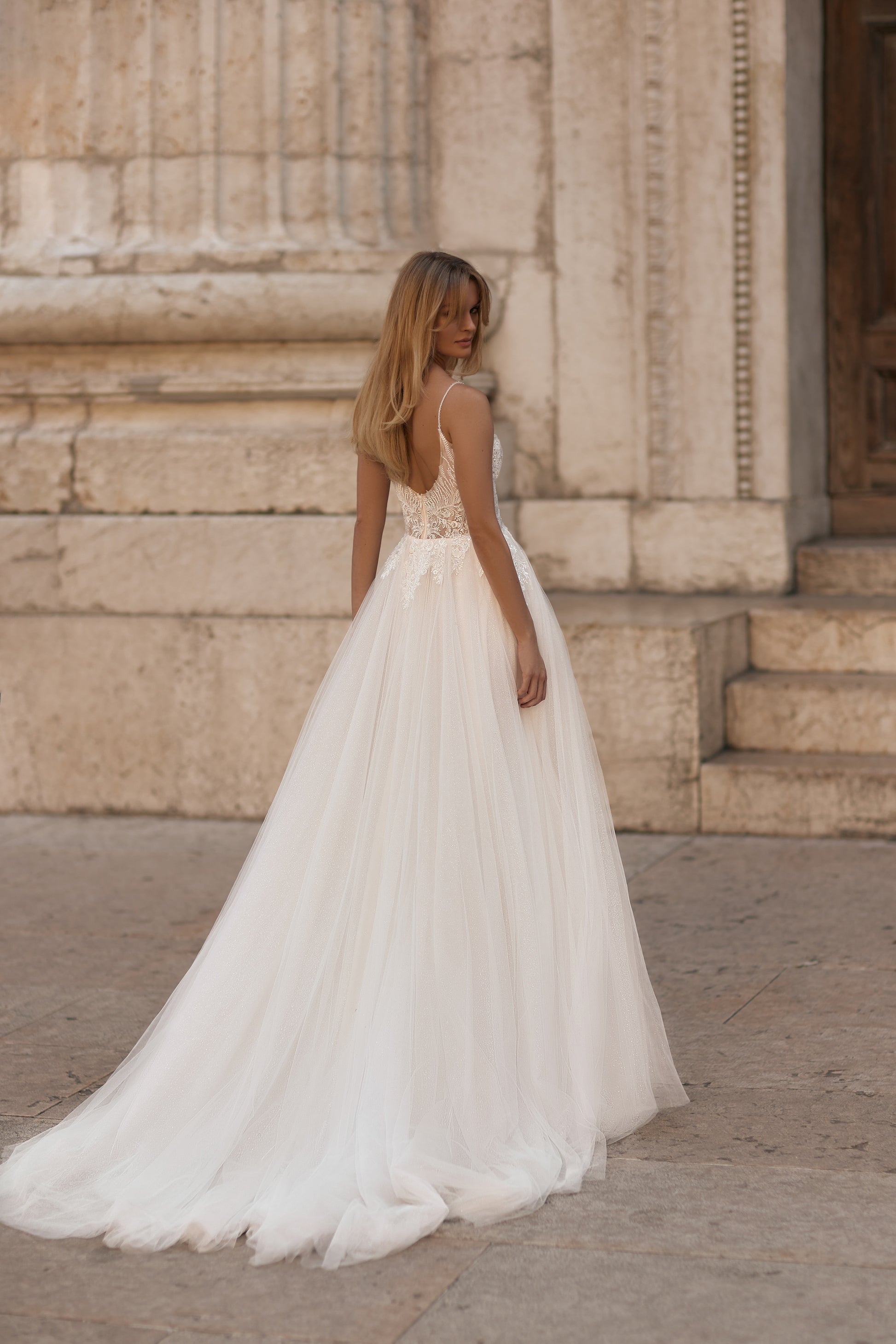 Bride wearing detailed lace bodice with shimmering floral accents and thin straps