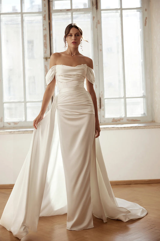 Bride in an elegant ivory satin sheath gown with off-shoulder neckline and side slit.