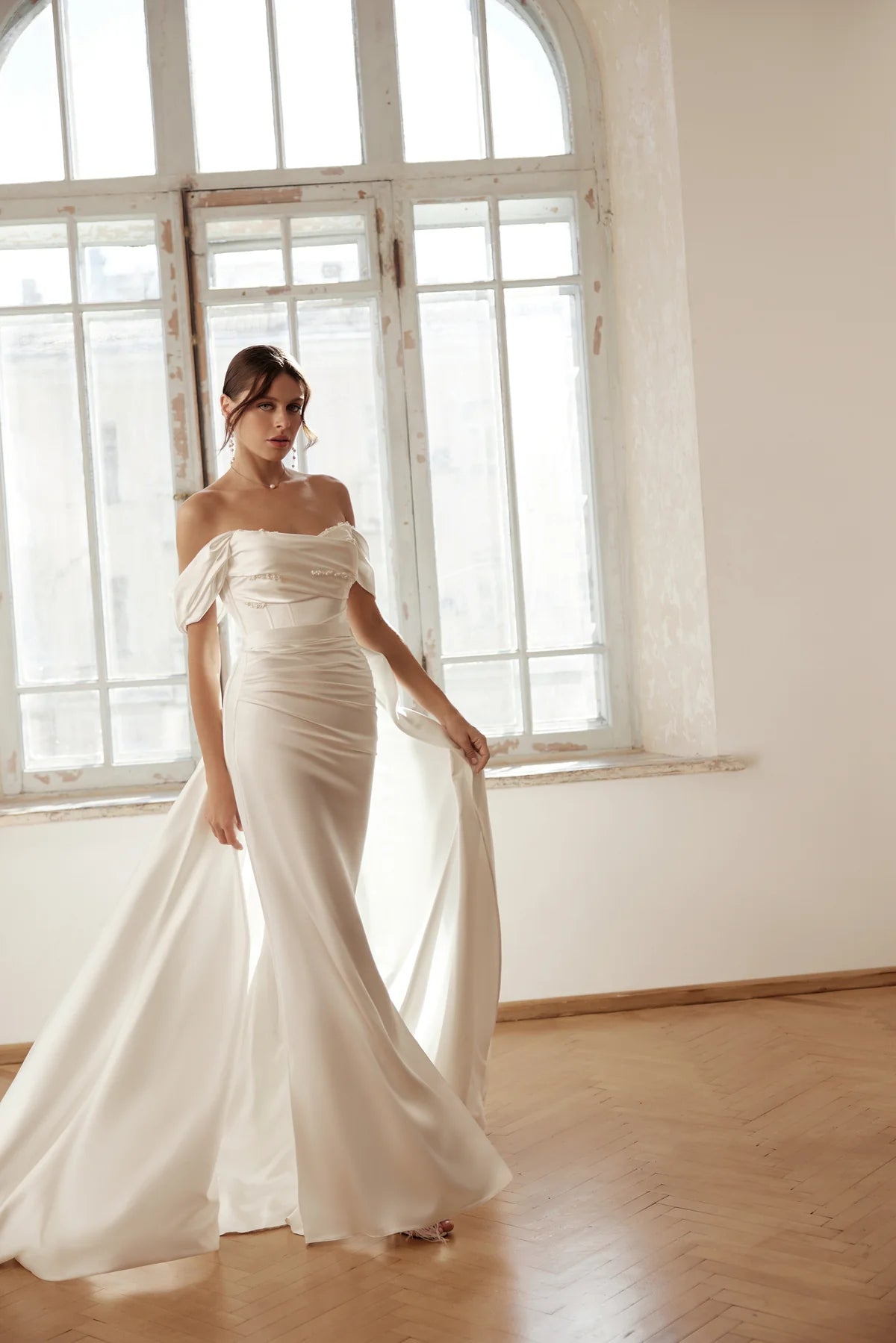 Bride showcasing the sleek silhouette of the sheath gown, holding fabric in hand.