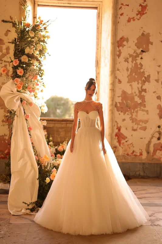 Bride in a ball gown with structured corset, pearl-draped shoulders, and voluminous tulle skirt
