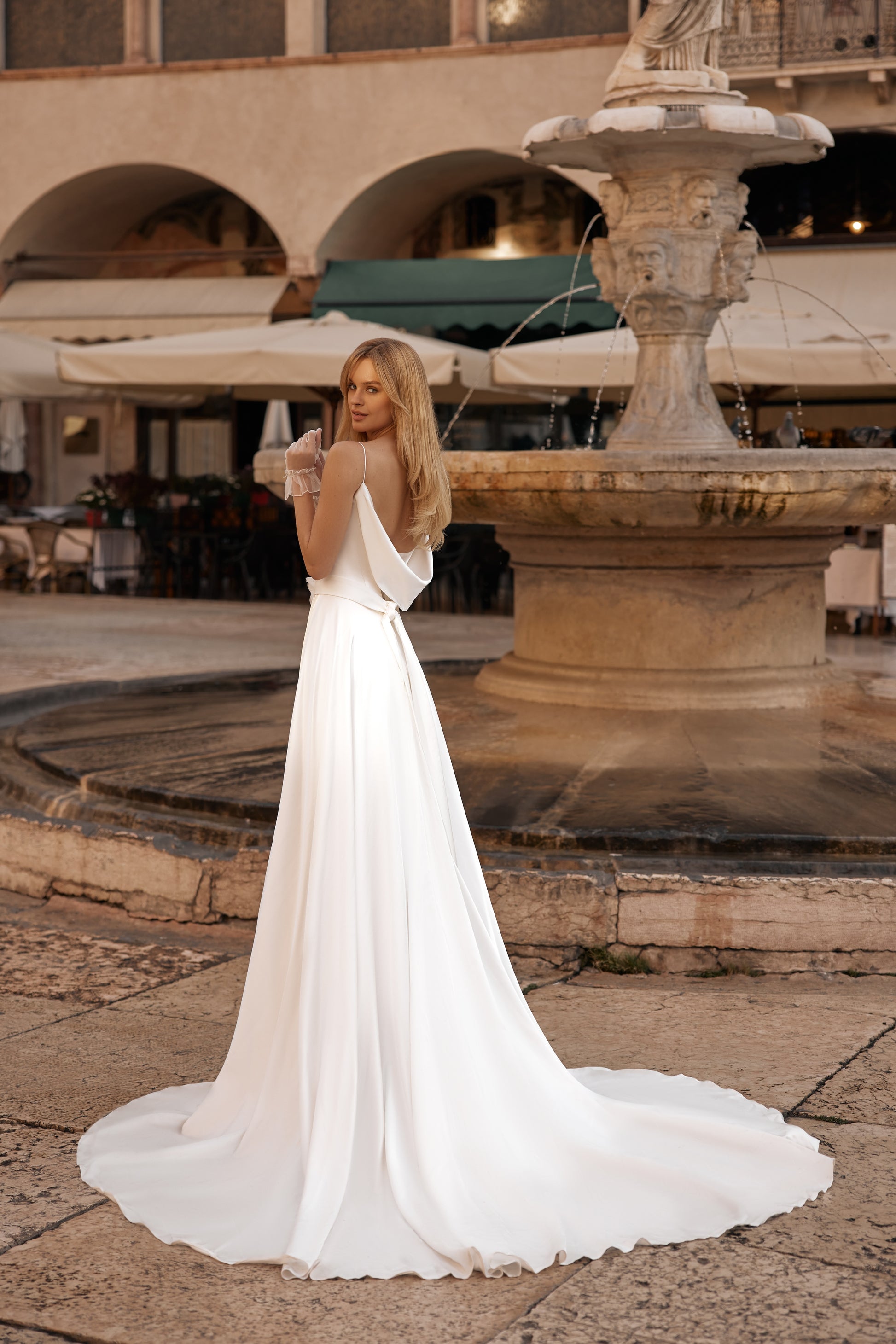 Open-back wedding dress with floral waist belt and elegant trailing skirt
