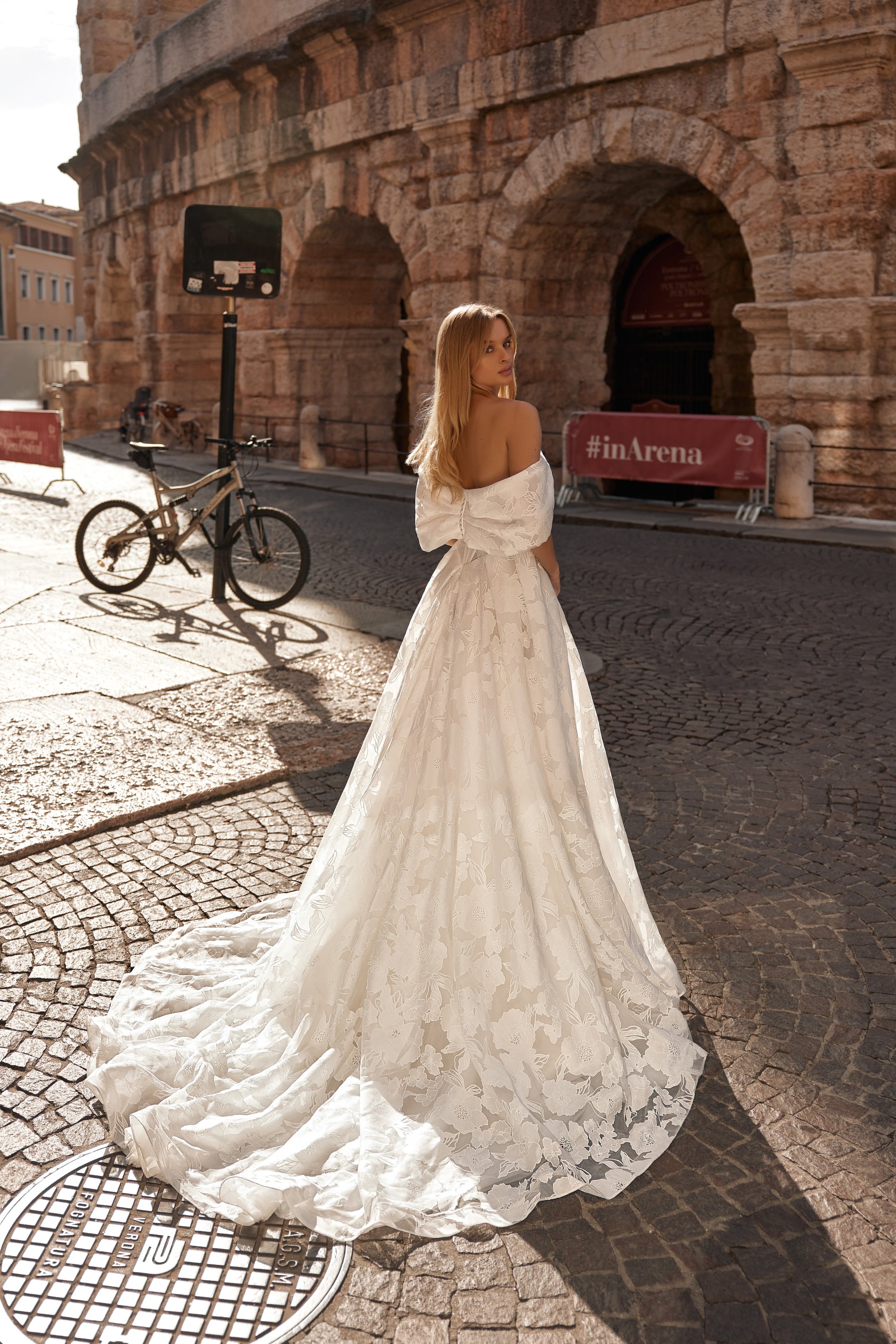 Side-back view of the Jane dress capturing the volume of the train and textured floral pattern.