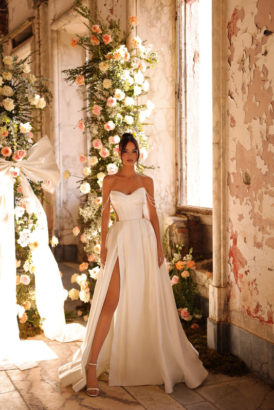 Bride in satin wedding gown with pearl shoulder drapes and thigh-high slit