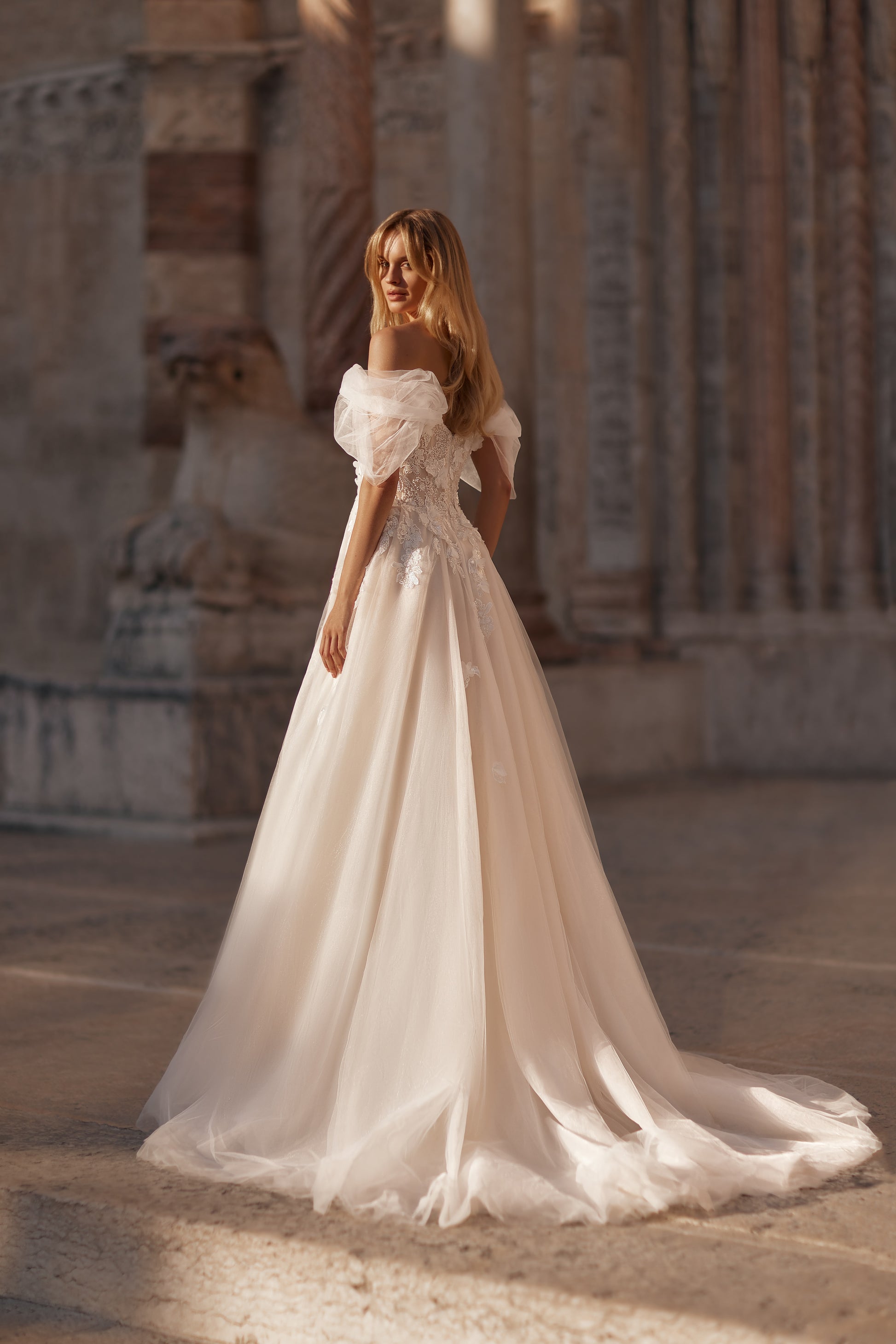 Woman in a white wedding dress standing in front of an architectural background