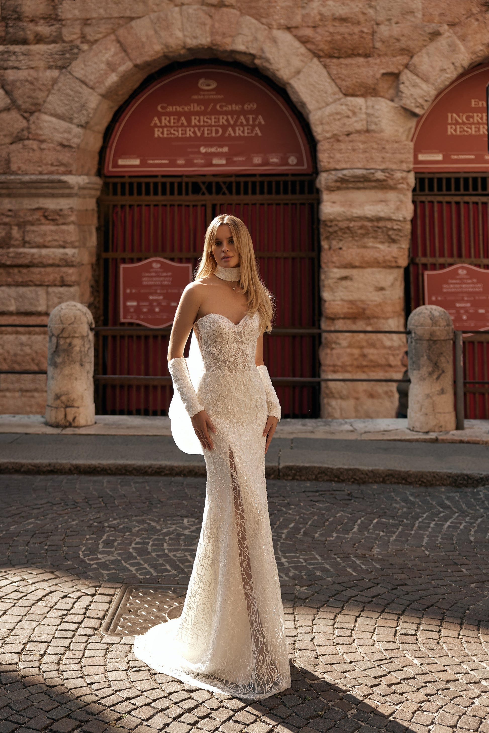 Bride in elegant mermaid gown with floral lace, off-shoulder sleeves, and long train