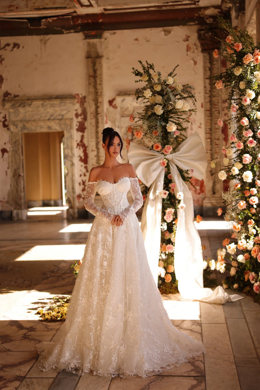 Bride in off-shoulder lace wedding dress with romantic floral arch