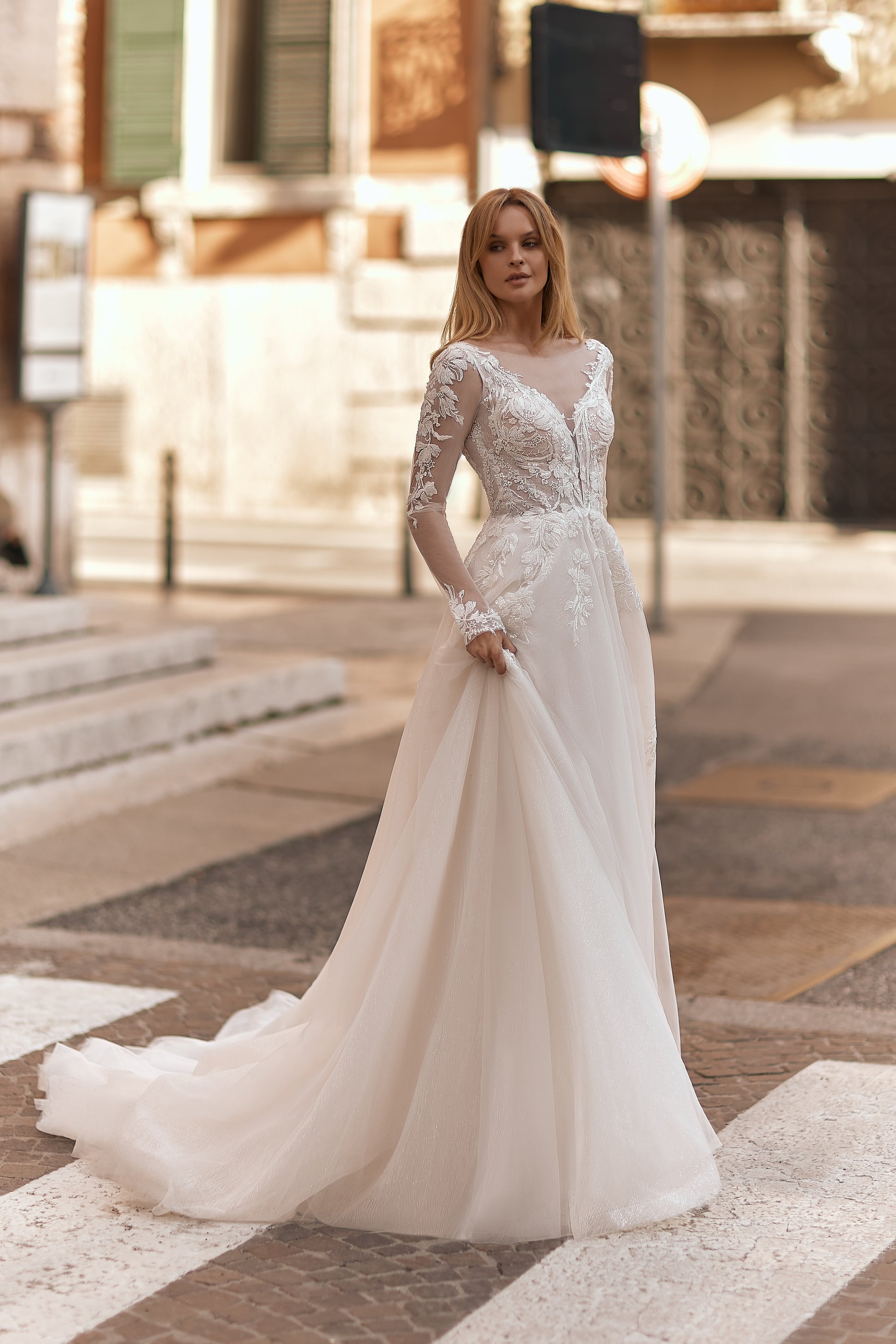 Bride wearing a delicate lace wedding gown with floral details and sheer long sleeves