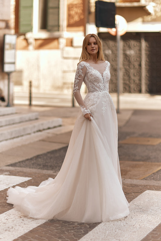 Bride wearing a delicate lace wedding gown with floral details and sheer long sleeves
