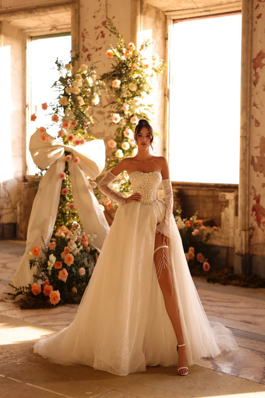 Bride in fairytale wedding gown with leg slit and elegant floral backdrop
