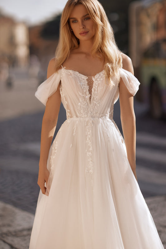 Bride in off-shoulder wedding gown with floral bodice and sheer skirt details