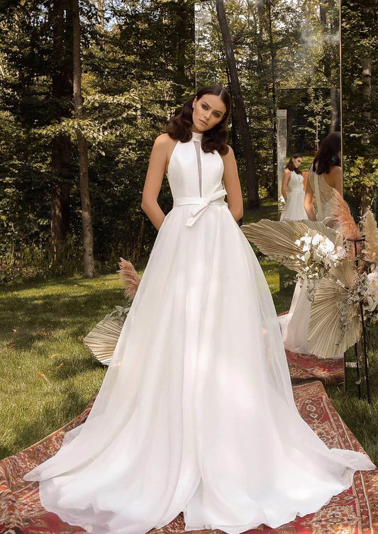 Bride in an ivory A-line wedding gown with a flowing skirt, standing in a forest setting.